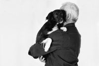 Aelterer Mann hat seinen schwarz weissen Hund auf dem Arm.jpg