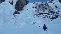 Ein Bergsteiger mit schwarzer Hose und blauer Jacke steigt den verschneiten Berg auf.jpg