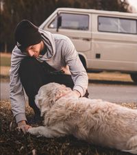 Ein Mann mit Muetze kniet vor einem Golden Retriever und haelt seine Pfote Ausschnitt.jpg